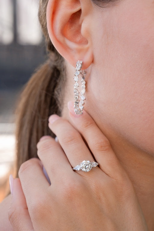 close up shot of womans ear with diamond earrings, and diamond ring